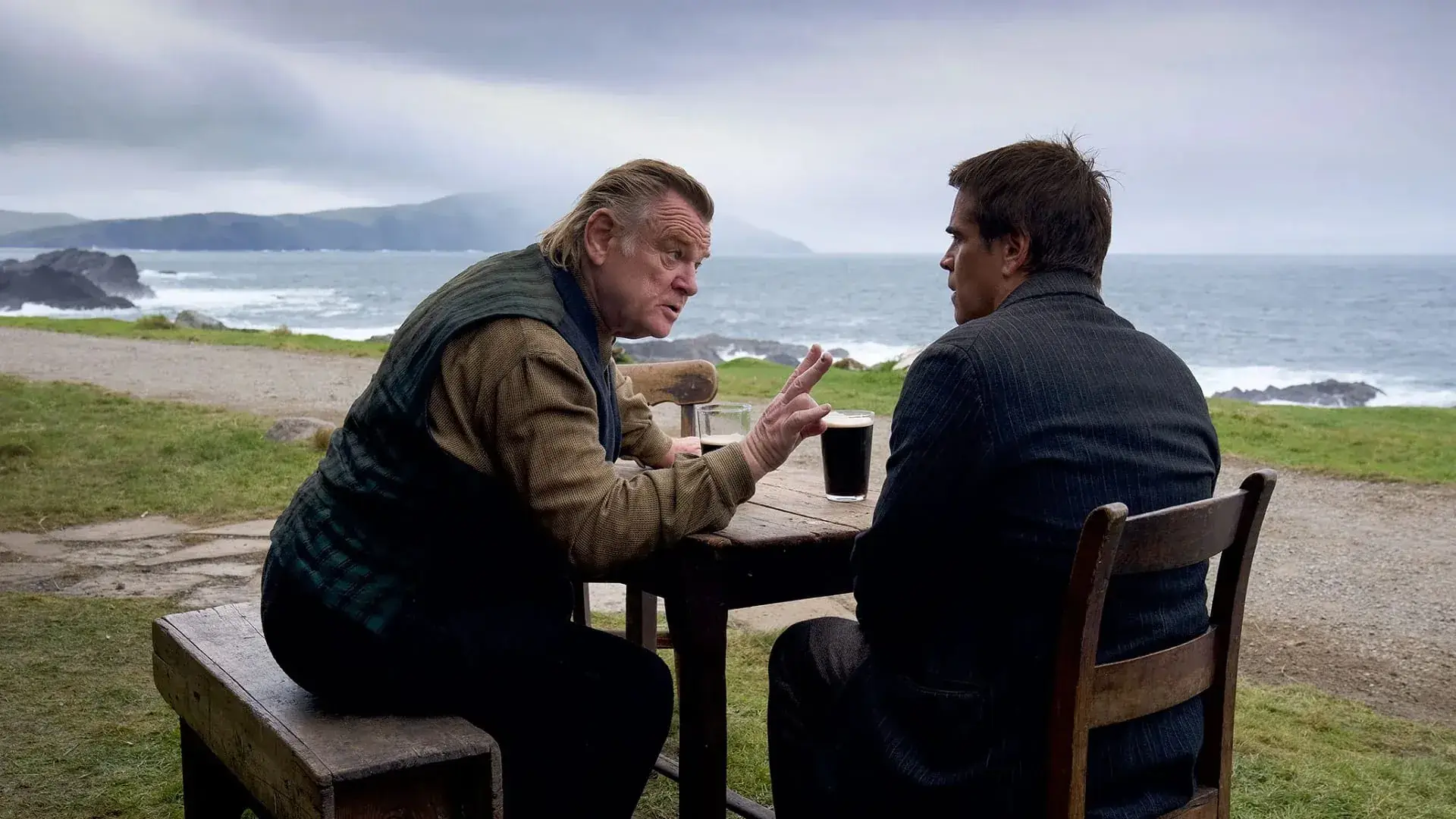 Protagonistas de la pelicula de cine Almas en pena de Inisherin hablando en una mesa al lado del mar