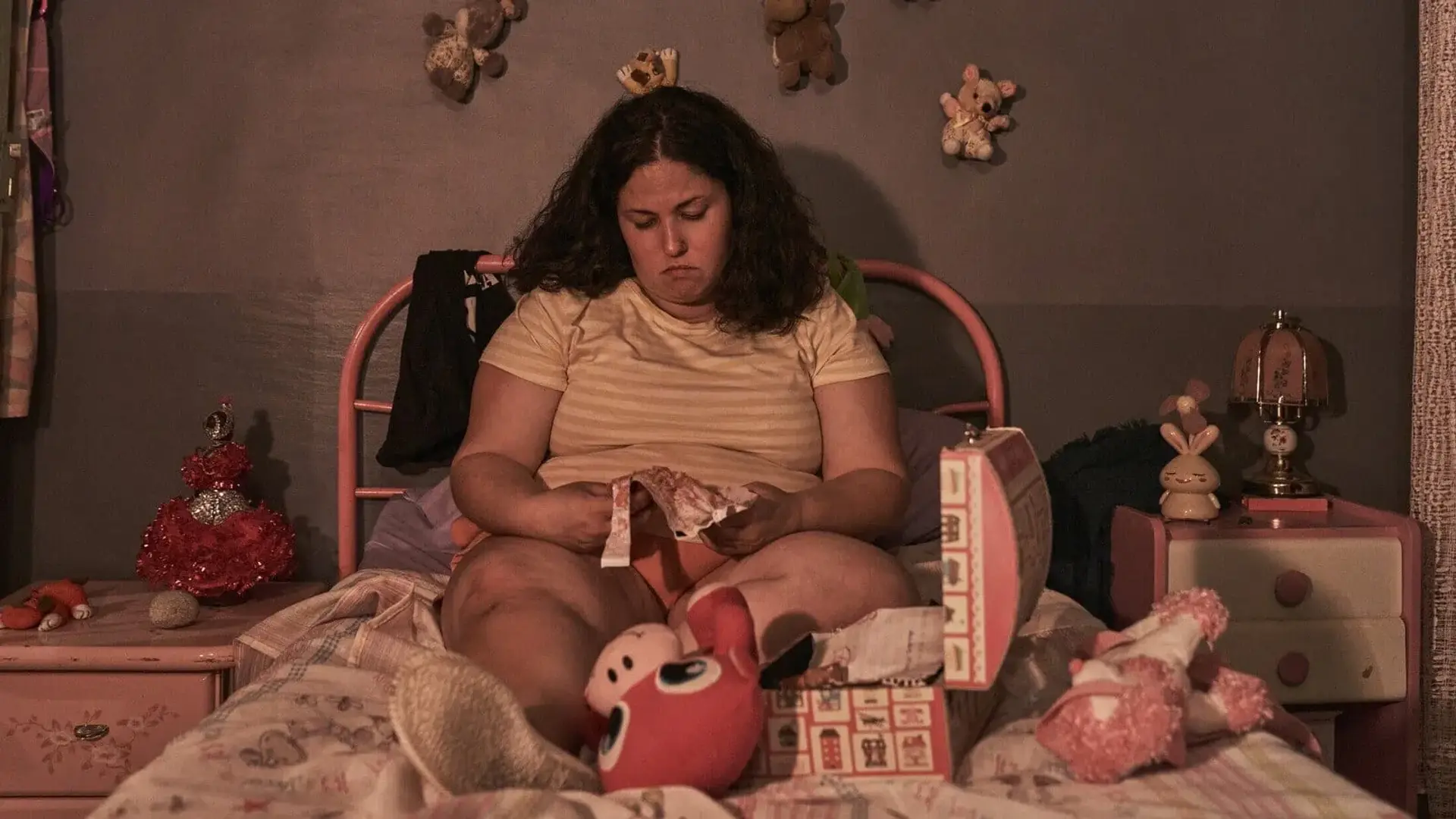 Protagonista de la pelicula Cerdita sentada en una cama con un gesto triste