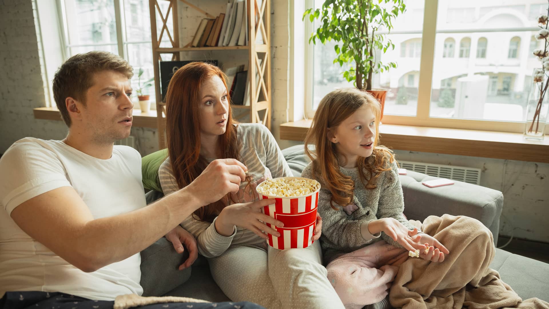 Familia come palomitas mientras ve con interés una película de disney plus en su smart tv