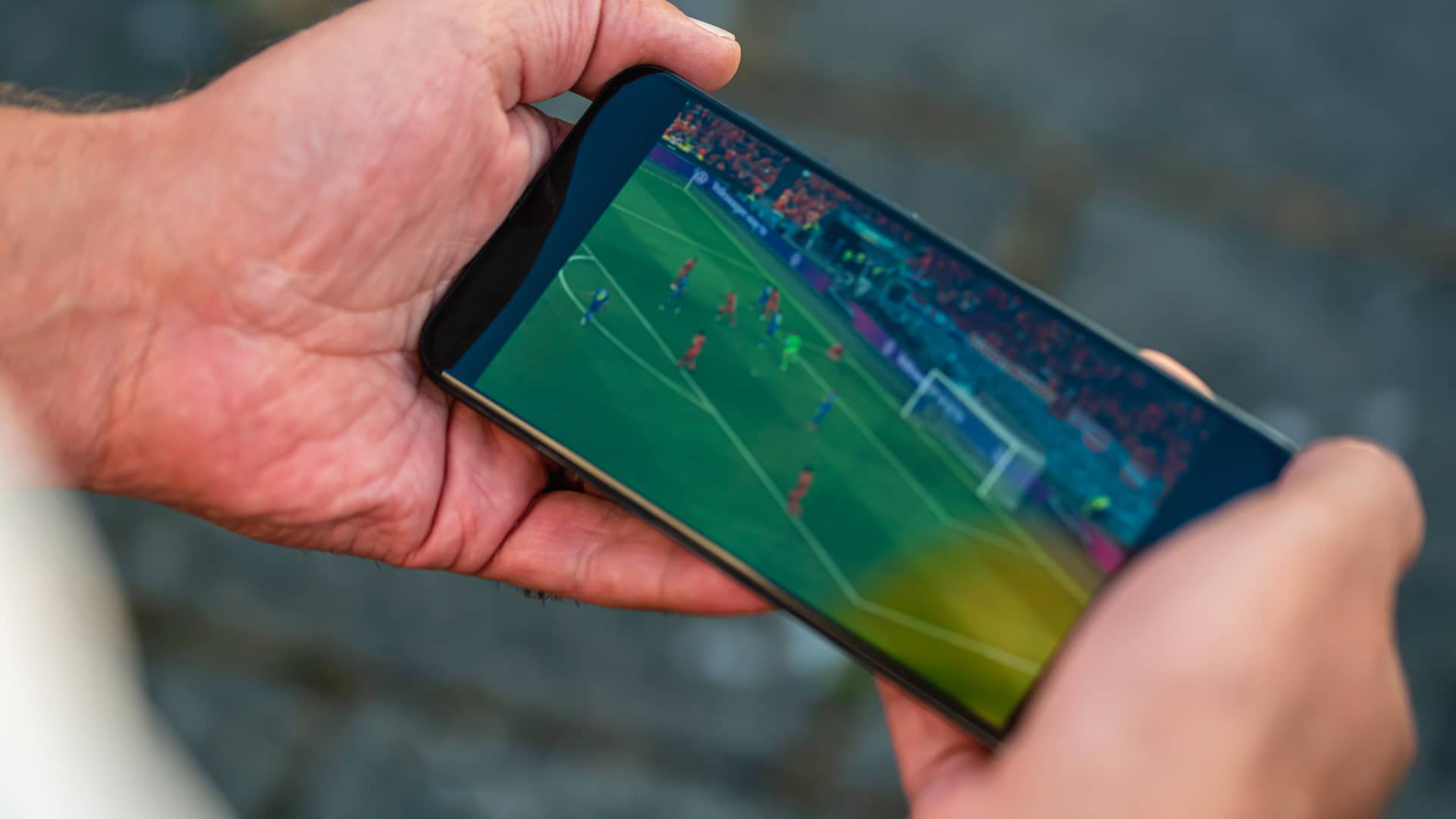 persona viendo un partido de futbol en steaming con la app de fotters en su telefono movil